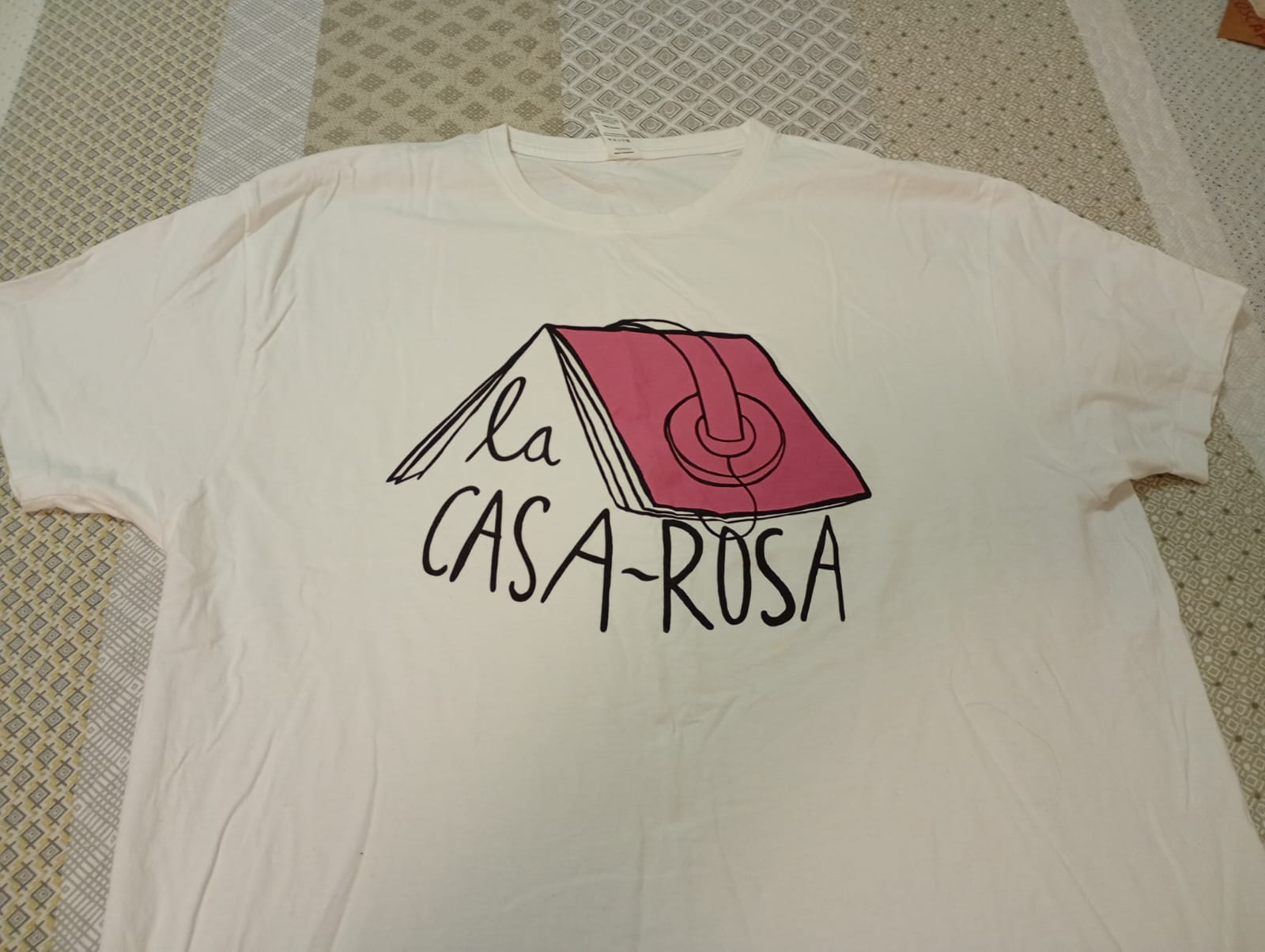 Camiseta blanca con logo de La Casa Rosa en color rosa y negro