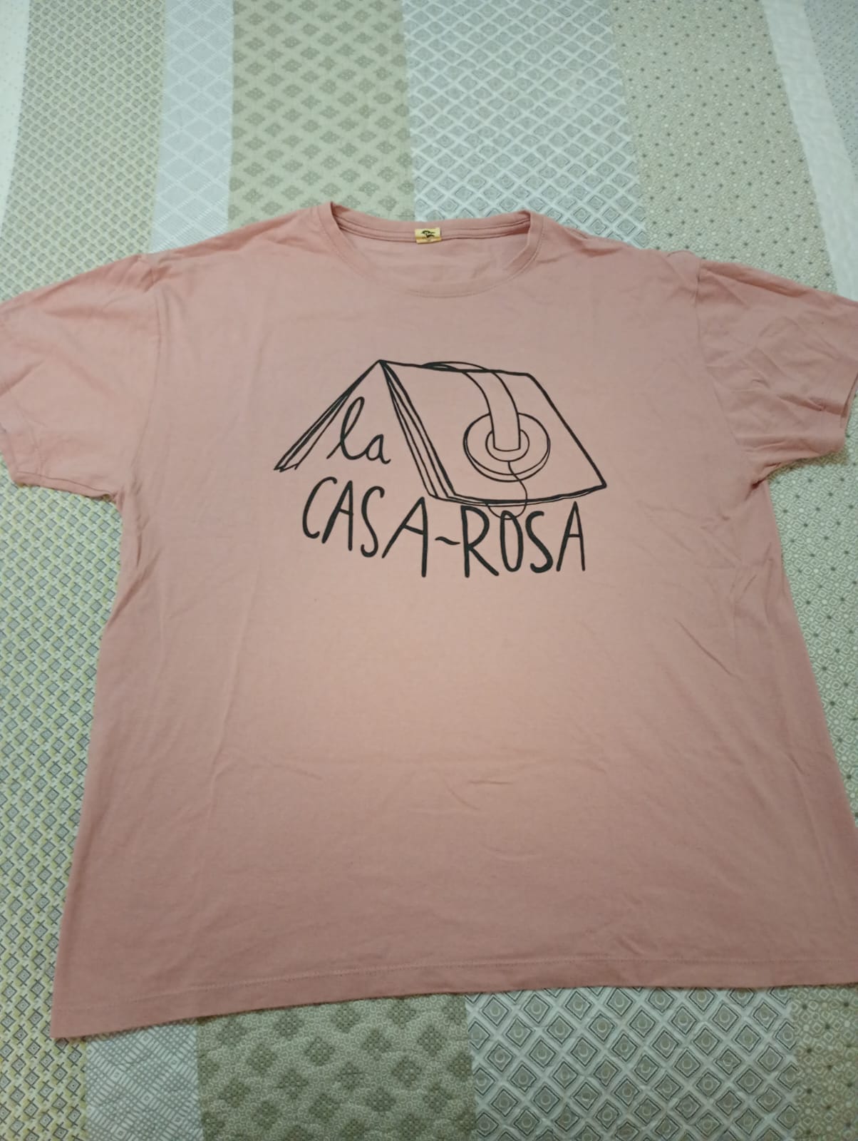 Camiseta rosa con logo de La Casa Rosa en color negro